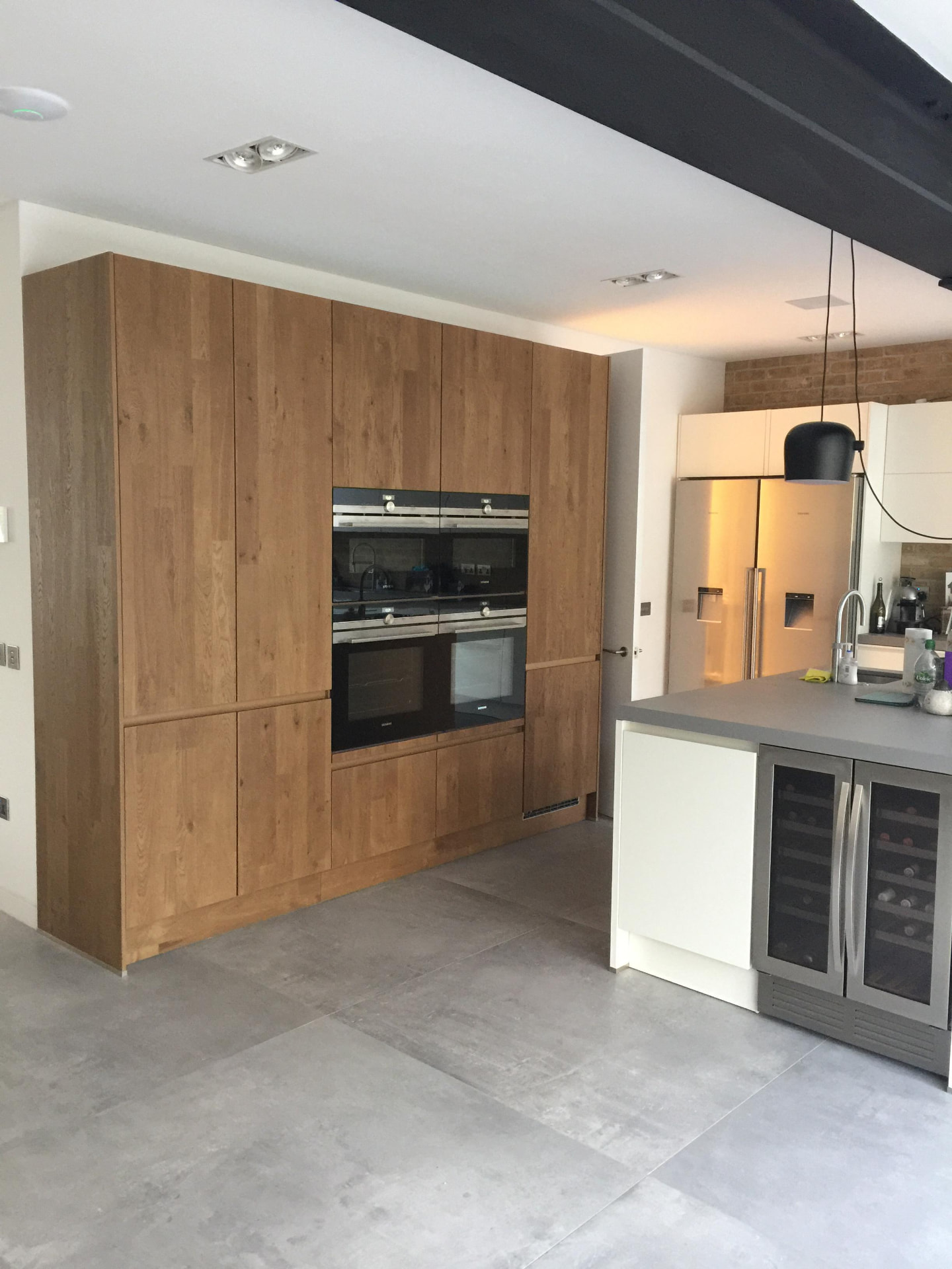 Handleless oak kitchen with integrated appliances and exposed steel beam