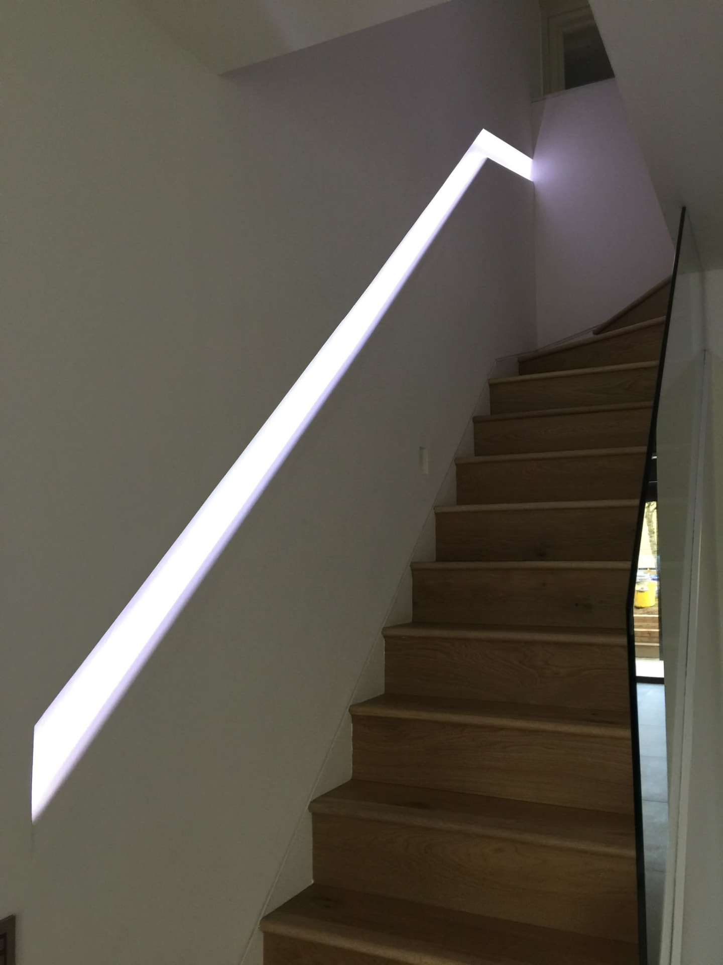 Oak staircase with recessed LED handrail and frameless glass balustrade