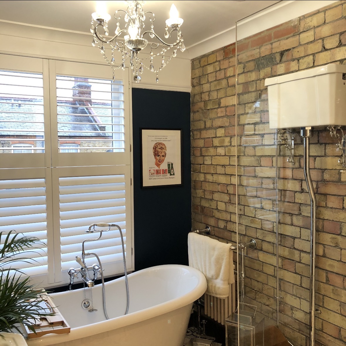 Bathroom with exposed brick wall, freestanding bath and chandelier