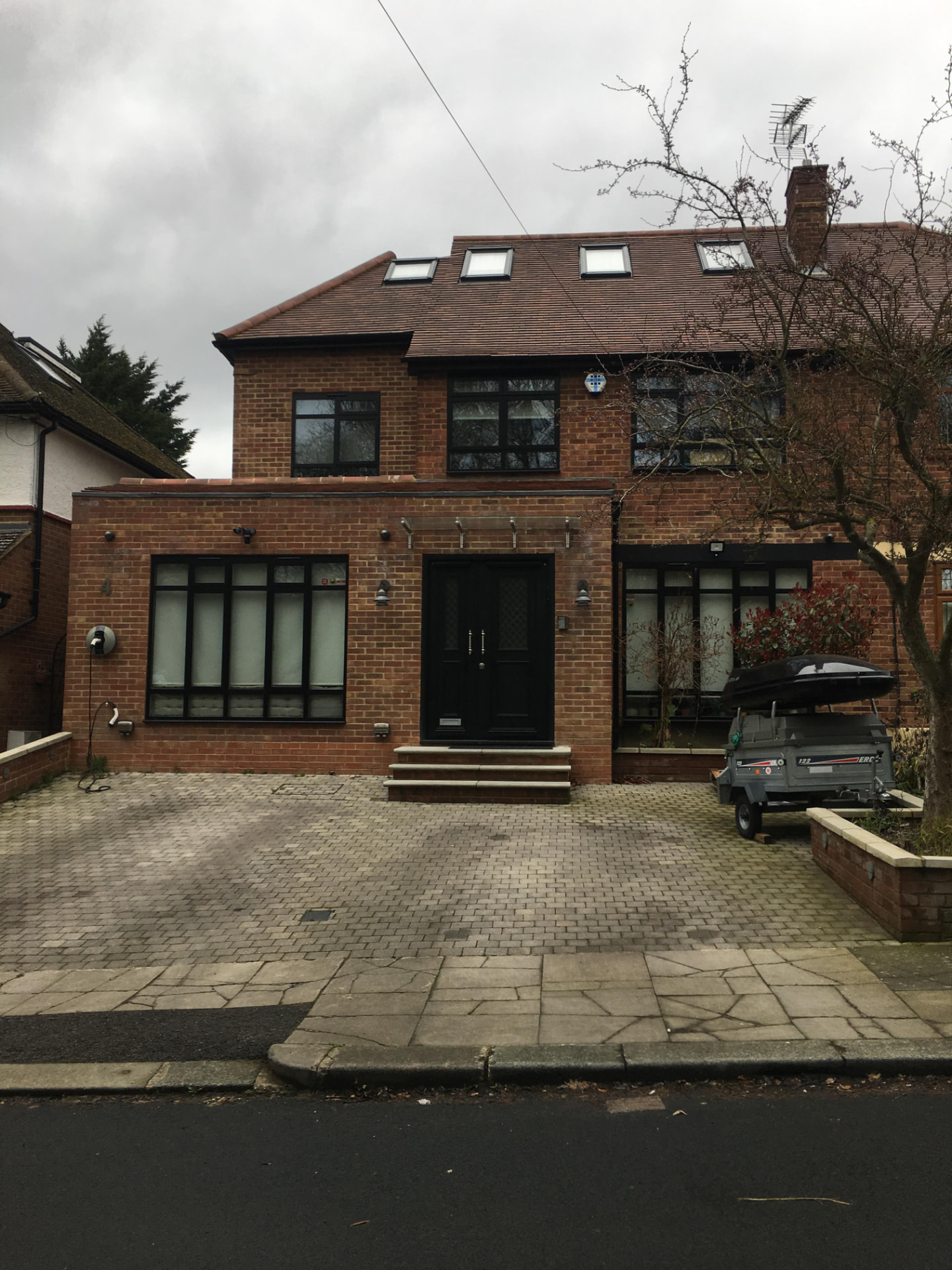 Brick front extension with loft dormer, black windows and block paved driveway